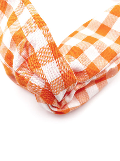 A handmade orange and white gingham plaid twist headband with an elastic band in the back.