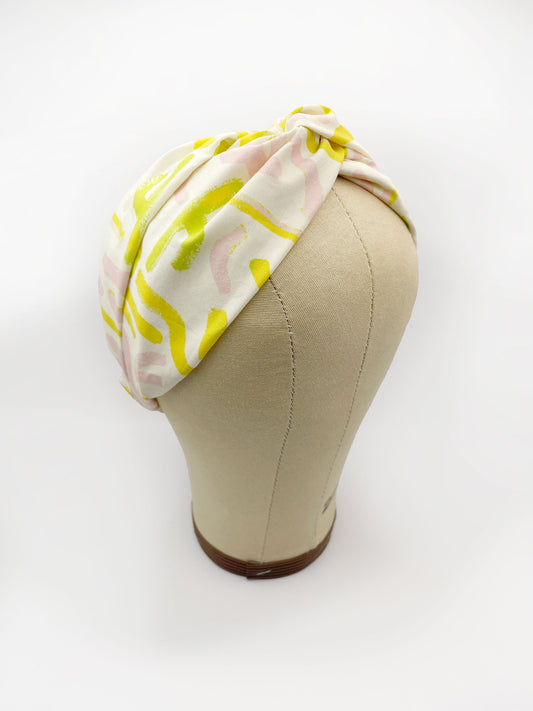 A twist headband featuring a yellow cactus print with hints of pink and green. The headband is modeled on a mannequin head.