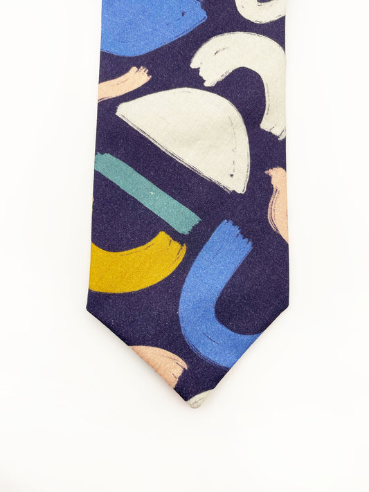 A cotton necktie with a colorful abstract print featuring various doodles. 