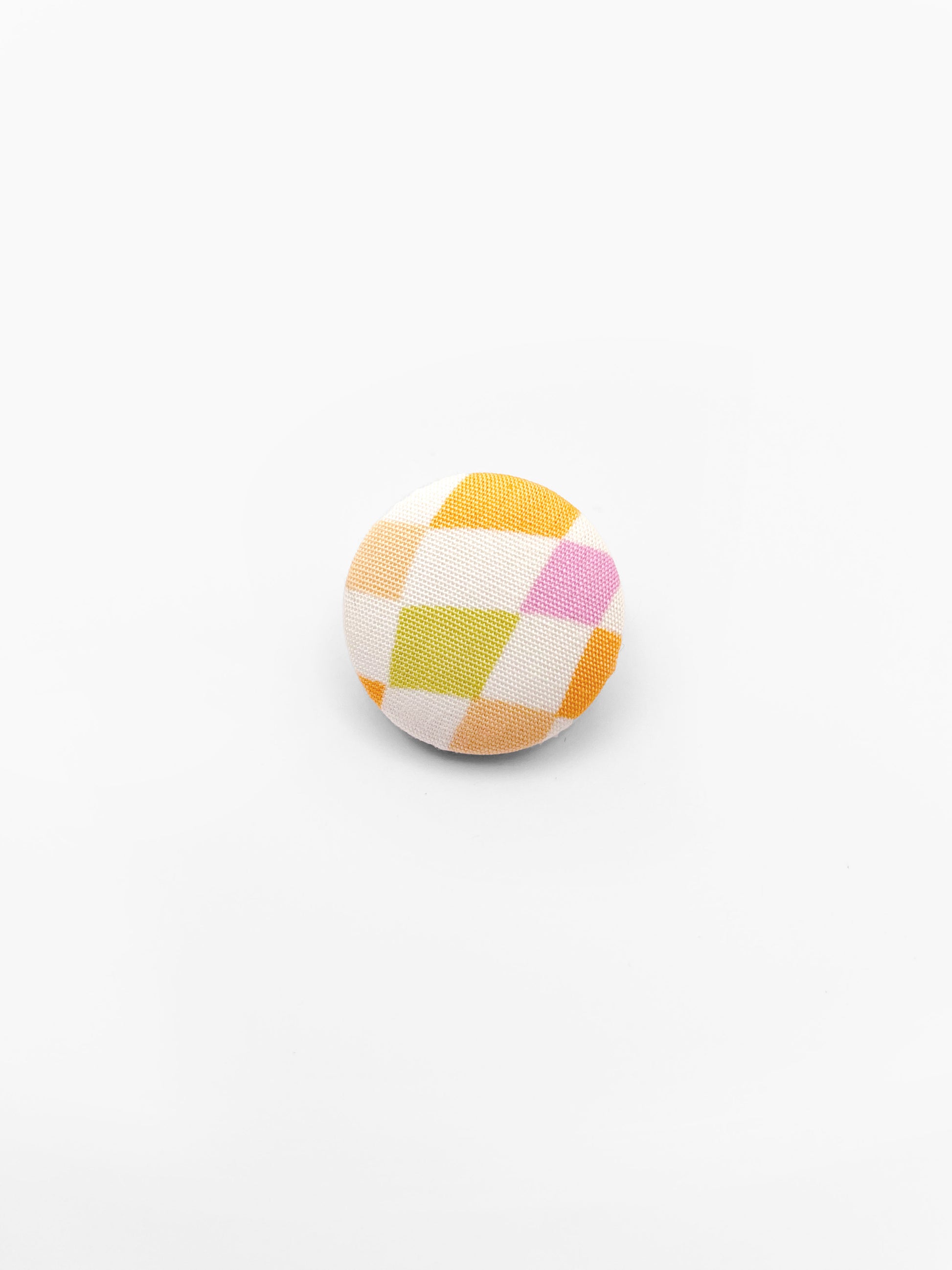 A fabric-covered lapel pin with a pastel checkered print.