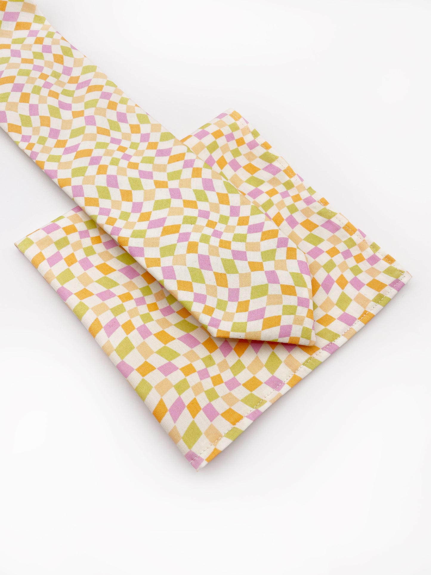 A handmade necktie with a pastel checkered print on top of a matching pocket square.