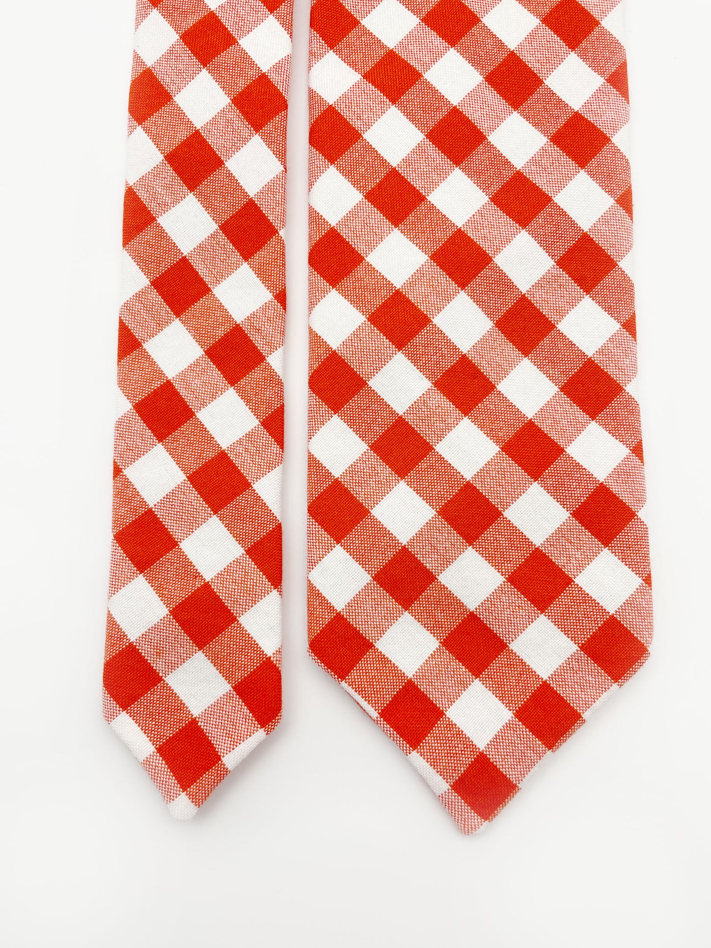 A cotton necktie with a vibrant red gingham plaid print.