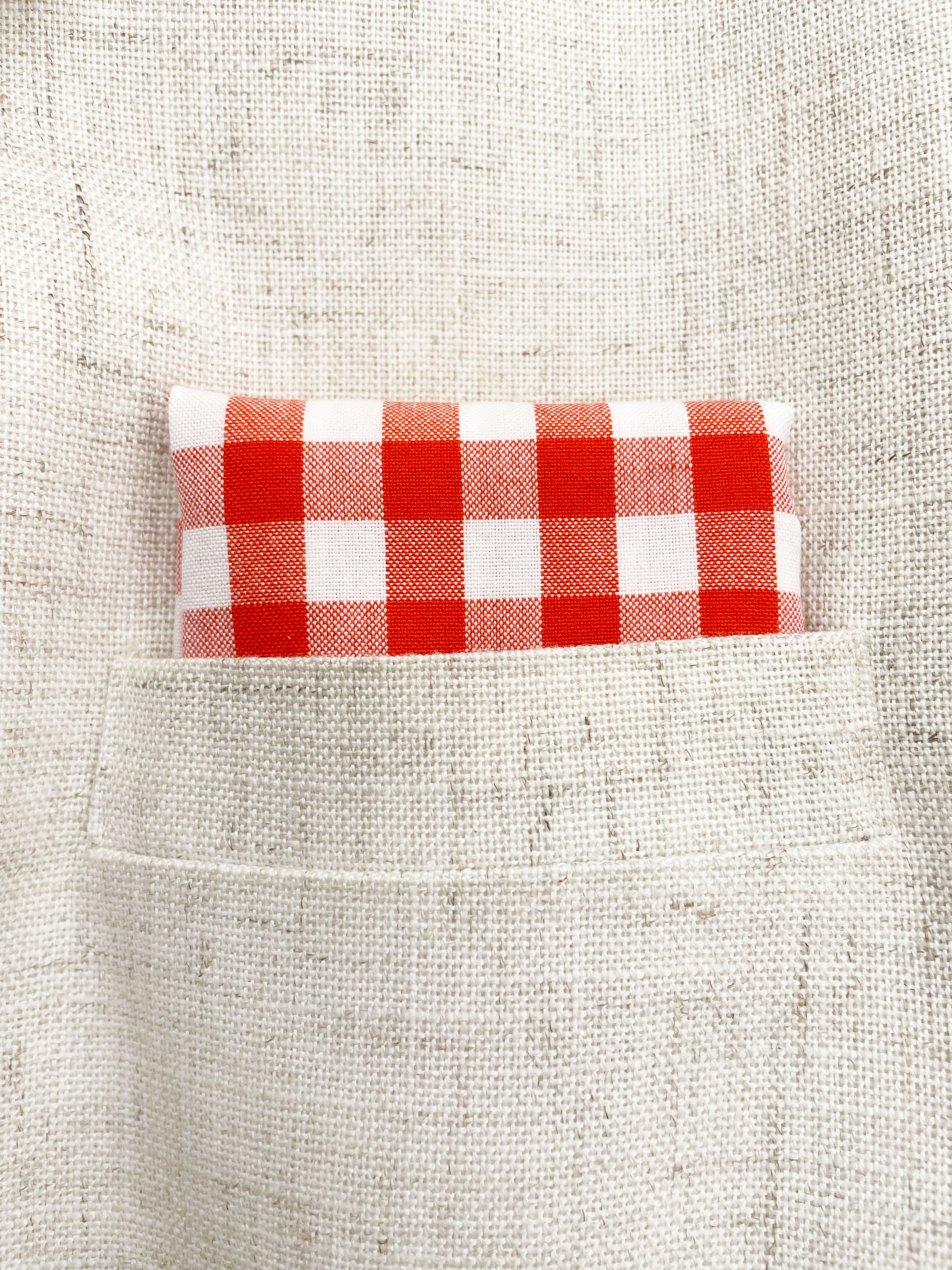 A cotton handmade pocket square with a red gingham plaid print. 