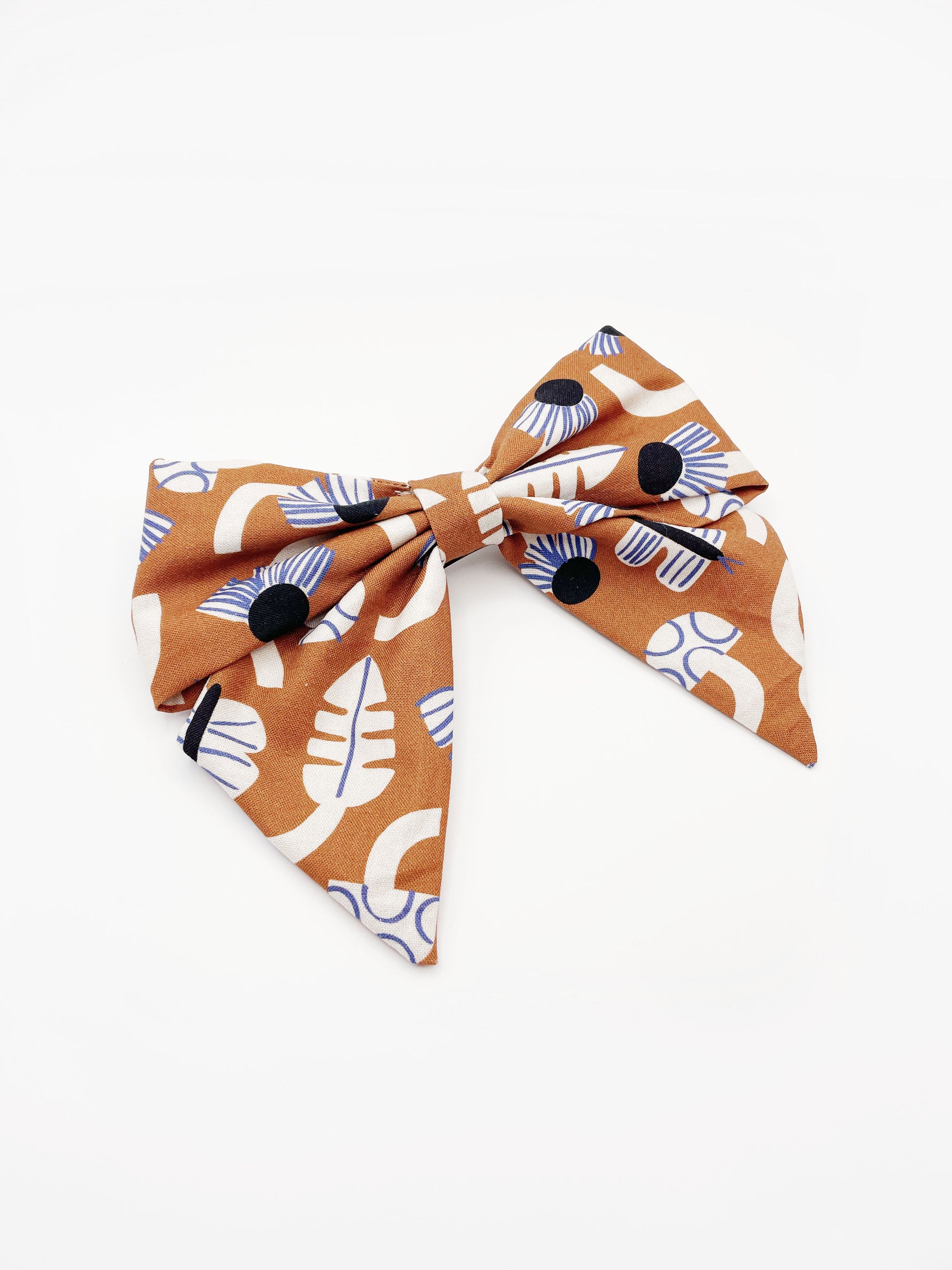 A large handmade hair bow with an abstract floral and leaf print in cream, black, and soft blue. 
