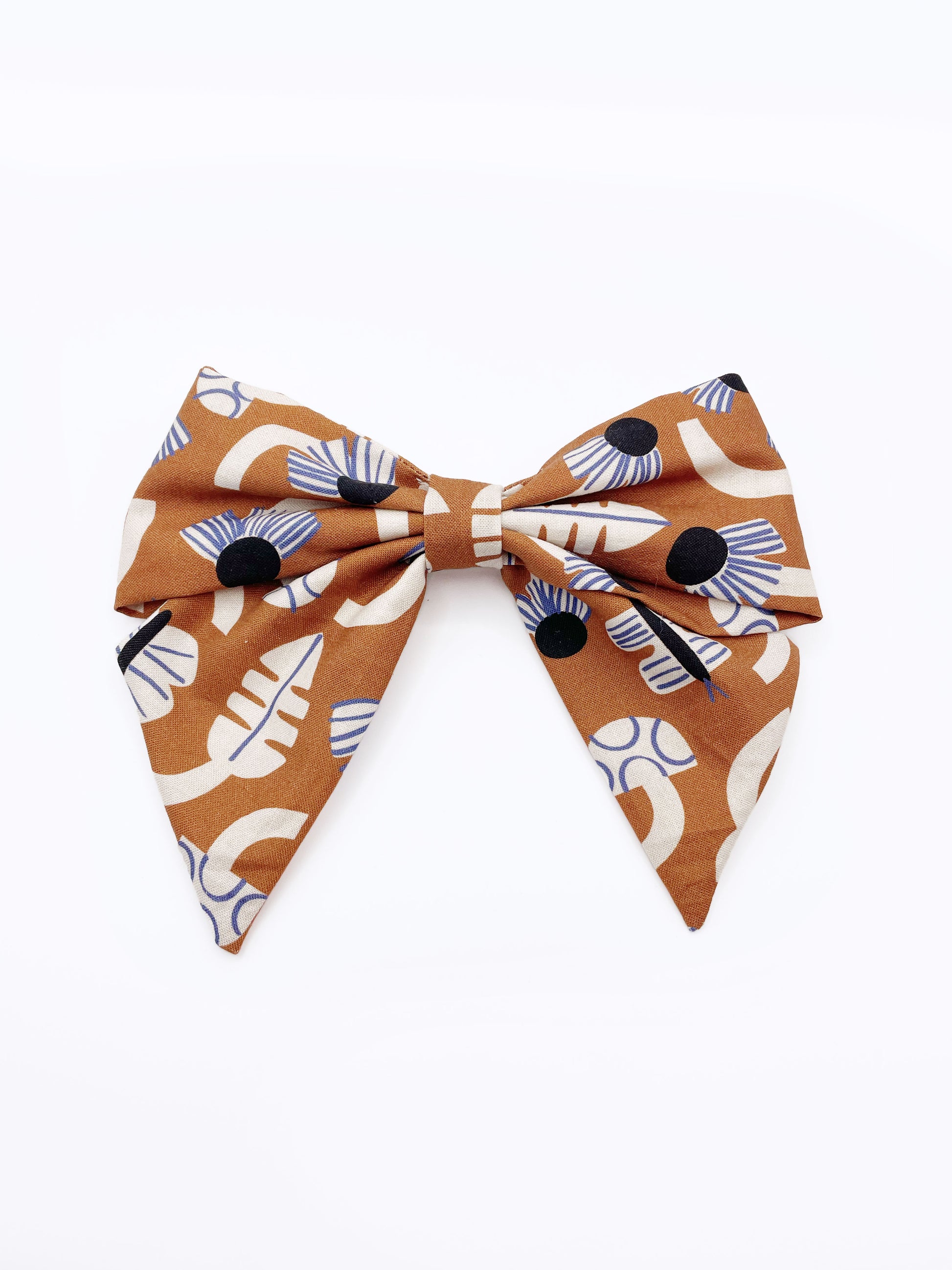 A large handmade hair bow with an abstract floral and leaf print in cream, black, and soft blue. 