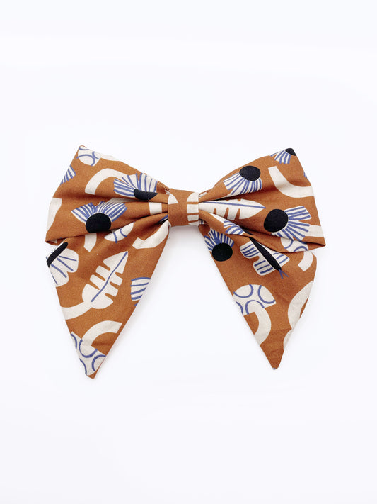 A large handmade hair bow with an abstract floral and leaf print in cream, black, and soft blue. 