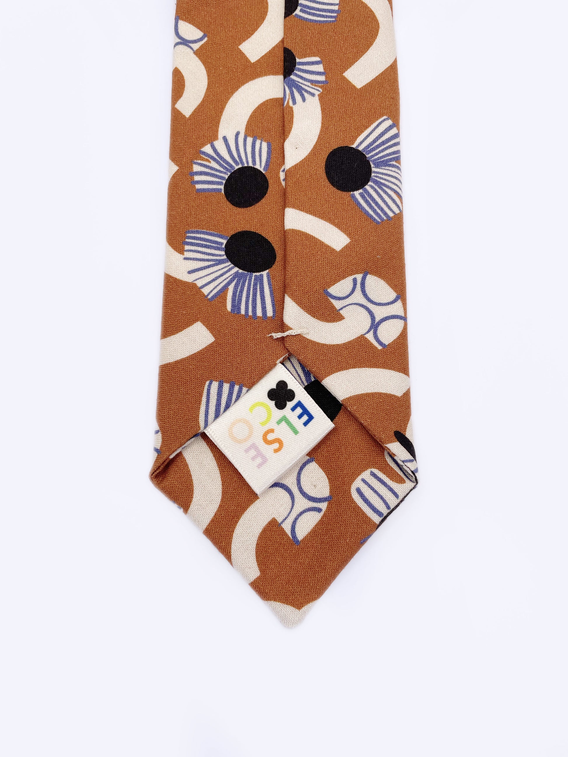 A necktie with an abstract print featuring flowers, leaves, mushrooms, and butterflies on a rich terracotta background. The color palette also consists of cream, black, and blue.