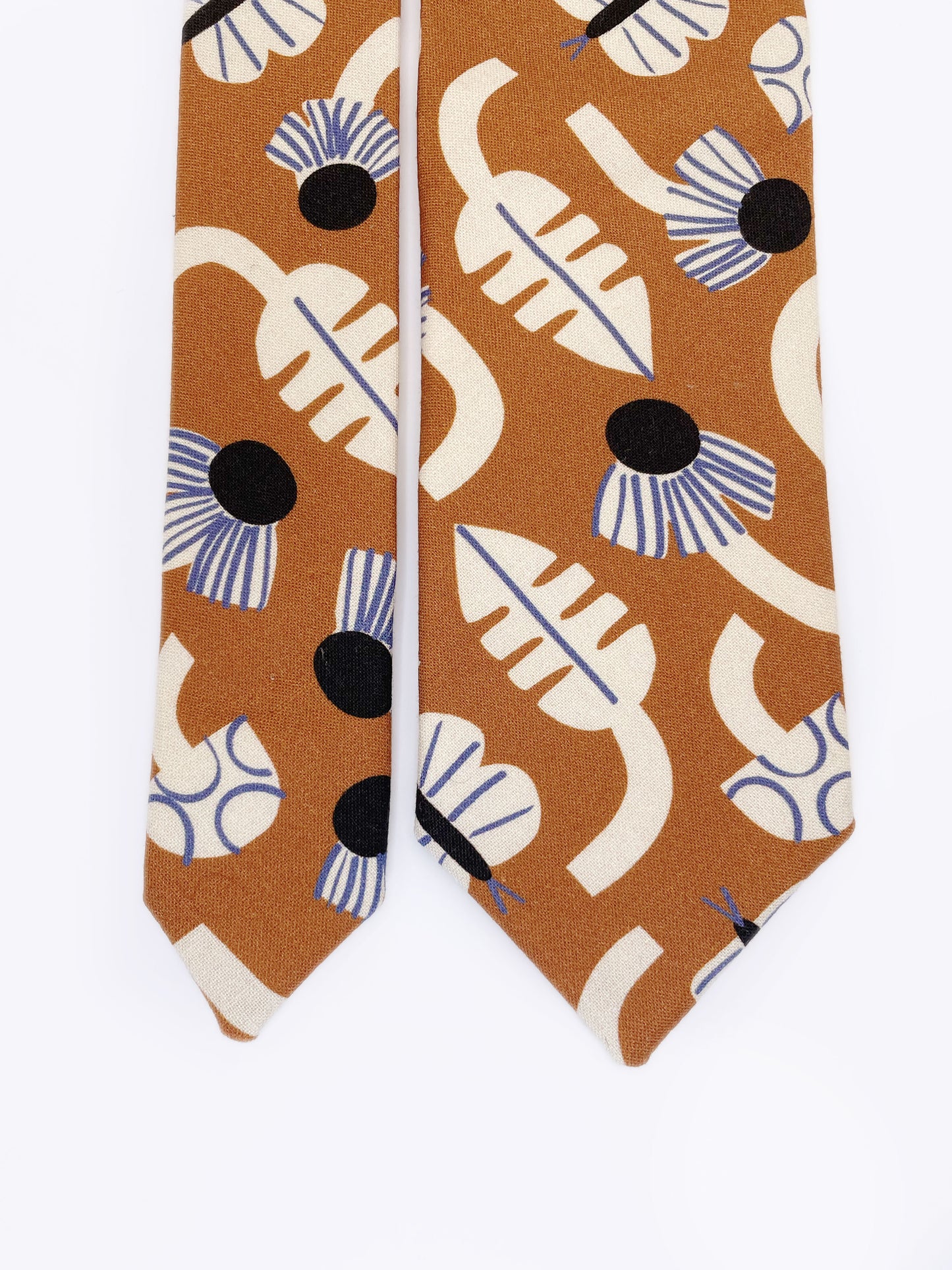 A necktie with an abstract print featuring flowers, leaves, mushrooms, and butterflies on a rich terracotta background. The color palette also consists of cream, black, and blue.