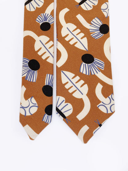 A necktie with an abstract print featuring flowers, leaves, mushrooms, and butterflies on a rich terracotta background. The color palette also consists of cream, black, and blue.