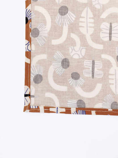 A pocket square with an abstract print featuring flowers, leaves, mushrooms, and butterflies on a rich terracotta background. The color palette also consists of cream, black, and blue.