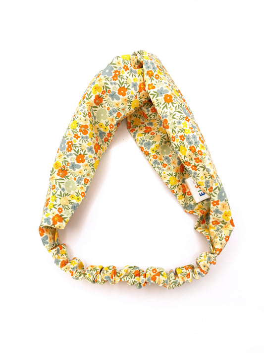 A cotton twist headband with a colorful ditsy floral print. The headband has an elastic band in the back.