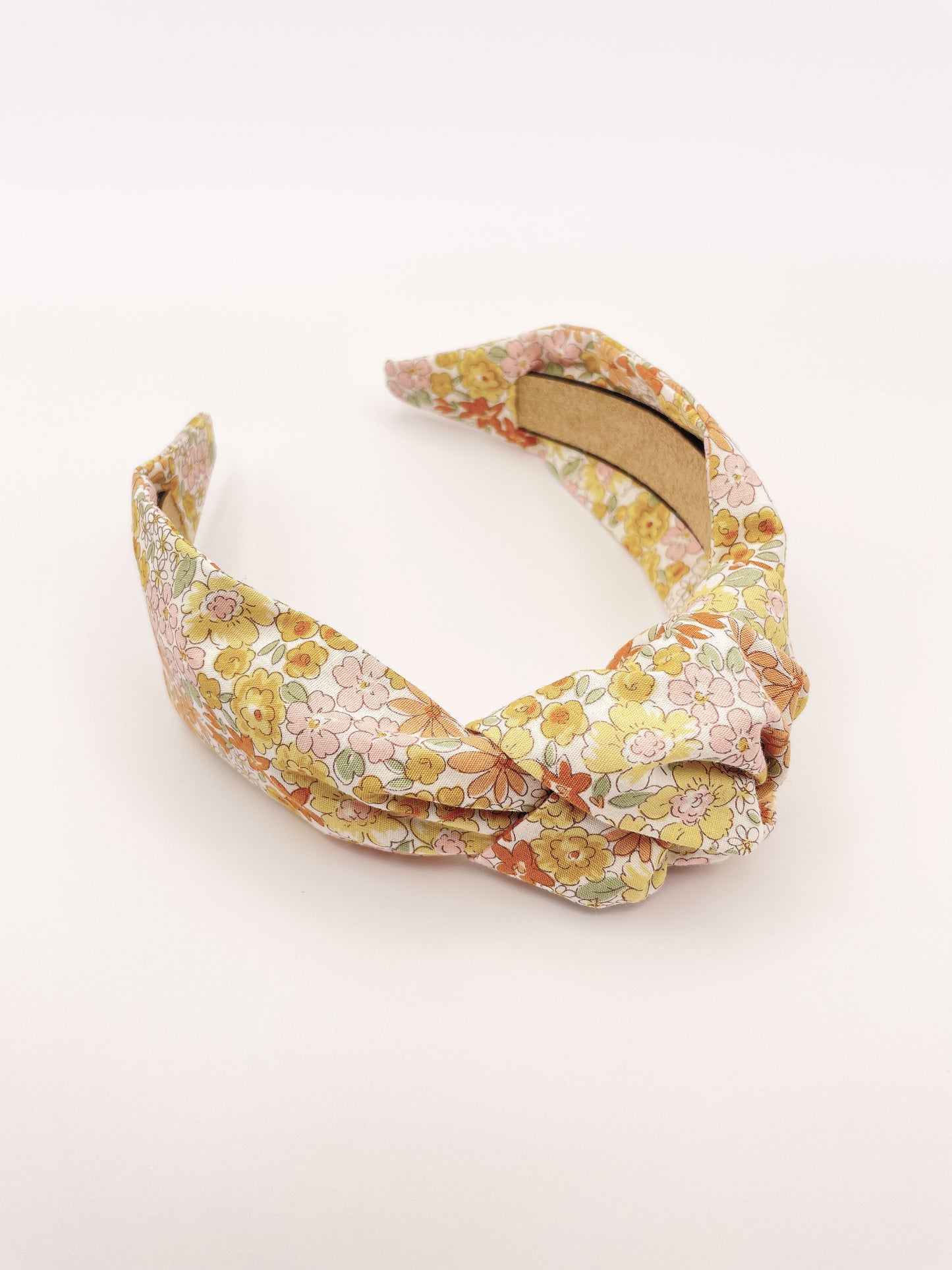 Handmade knotted headband with yellow flowers against an off white background