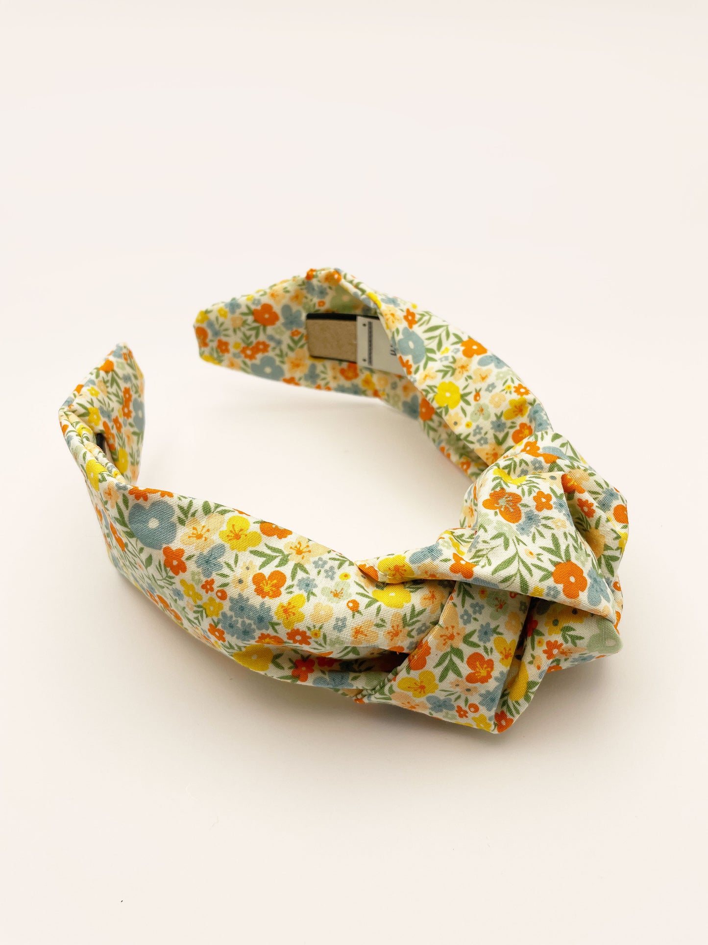 An off white knotted headband with a colorful ditsy floral print.