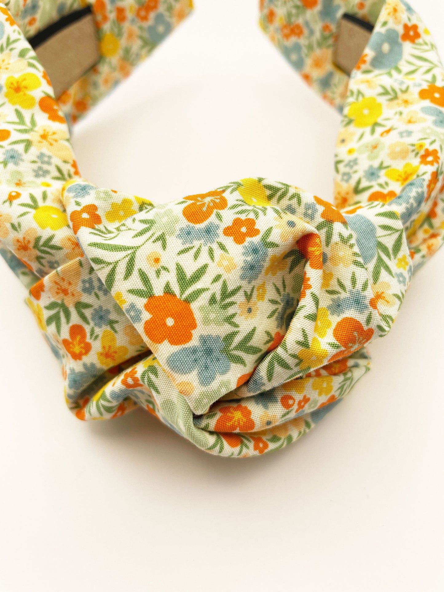 An off white knotted headband with a colorful ditsy floral print.