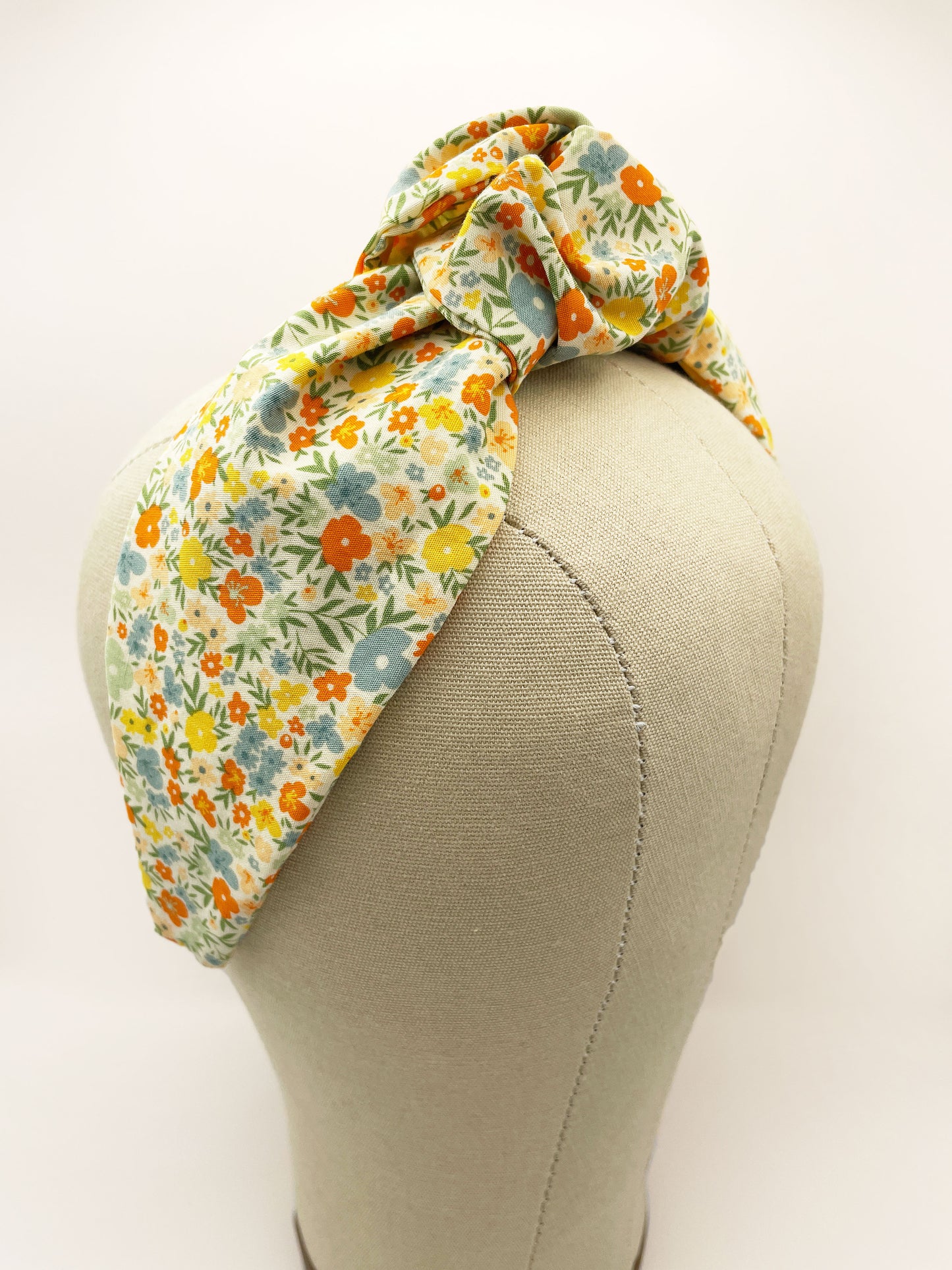 An off white knotted headband with a colorful ditsy floral print.