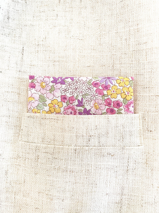 A handmade pocket square with purple flowers in a suit pocket.