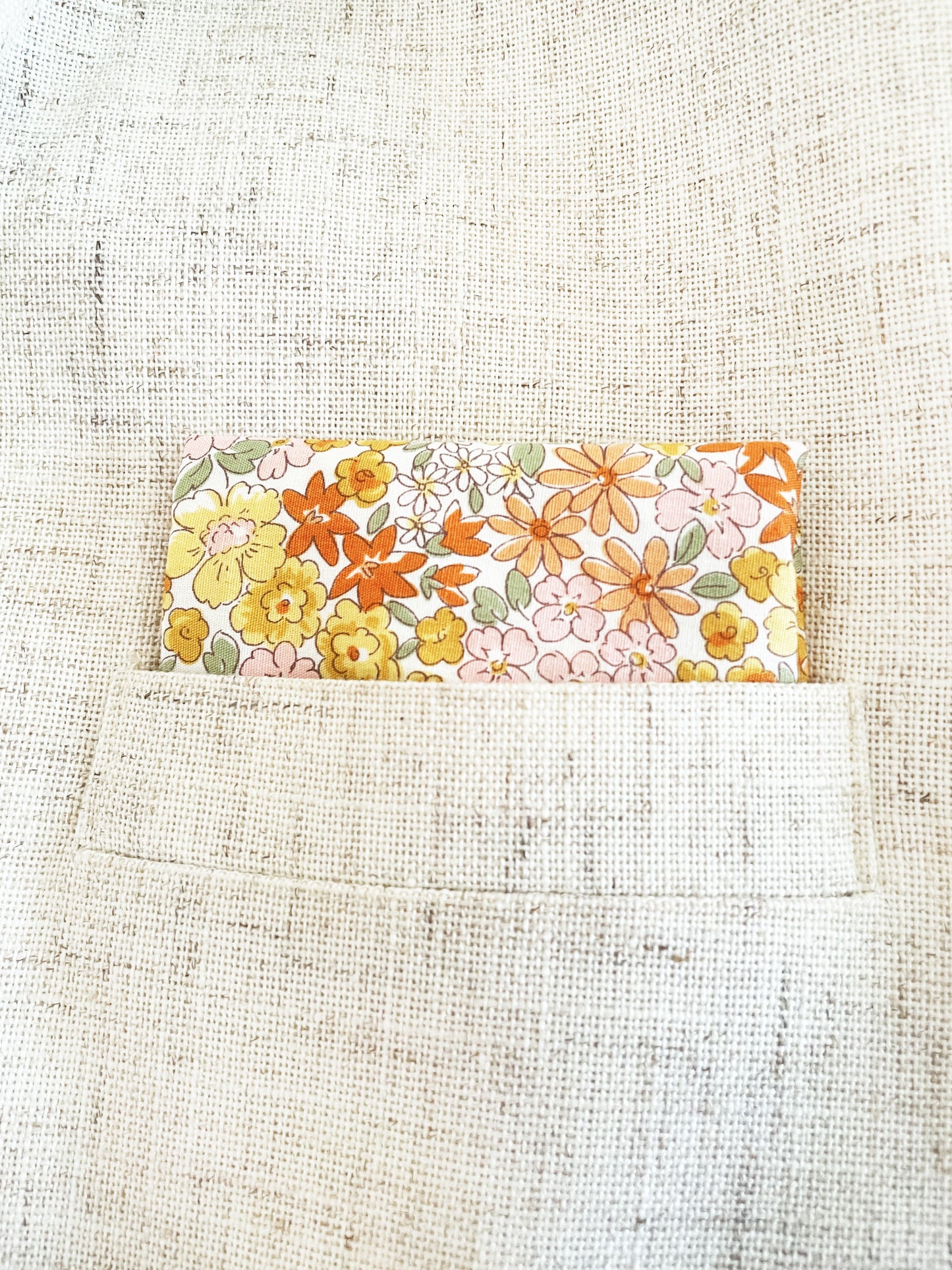 A handmade pocket square with yellow flowers against an off white background.