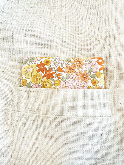 A handmade pocket square with yellow flowers against an off white background.
