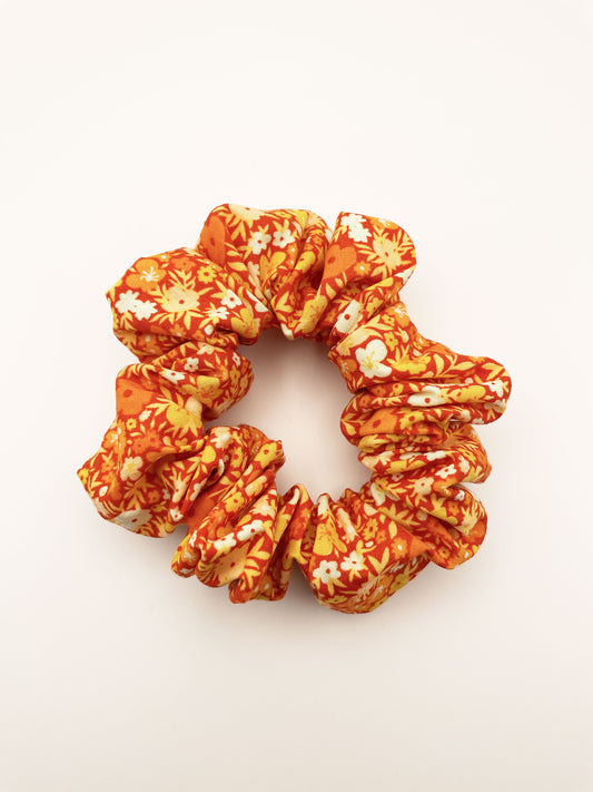 An orange scrunchie with a colorful ditsy floral print.